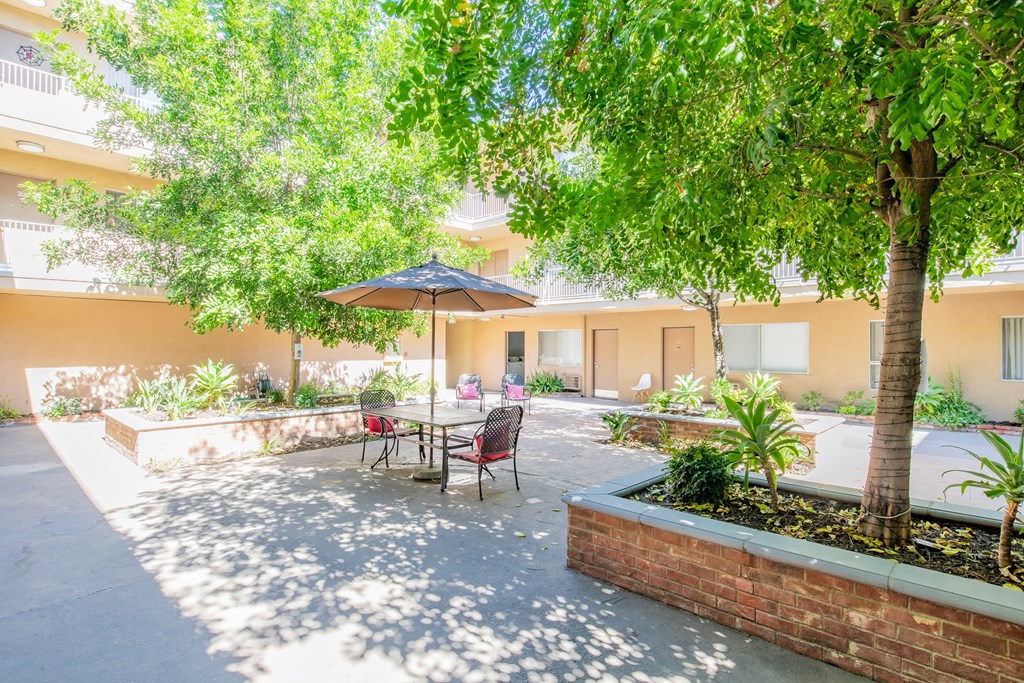 a courtyard with a table and chairs under a umbrella