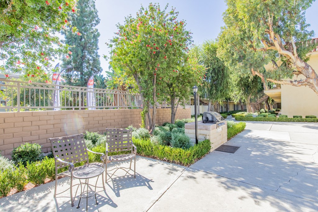 a patio with a table and chairs and a wall and trees