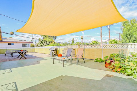 a patio with chairs and a table under a canopy