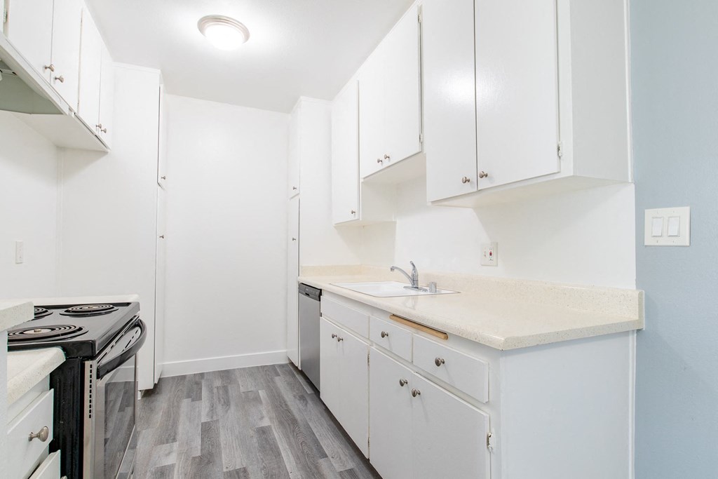 a white kitchen with white cabinets and a stove and sink
