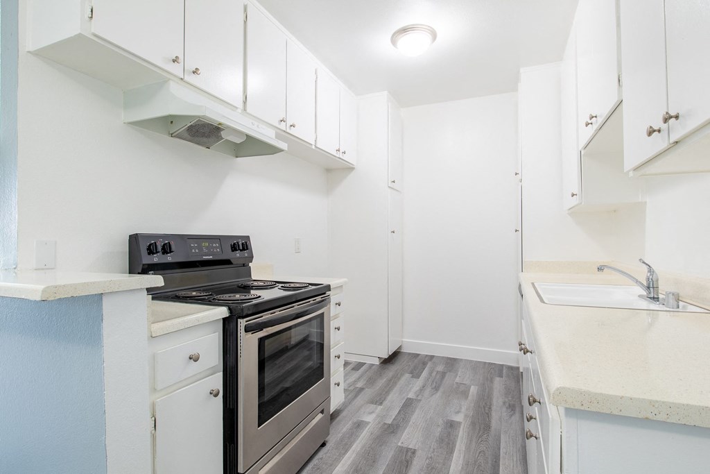 a white kitchen with stainless steel appliances and white cabinets