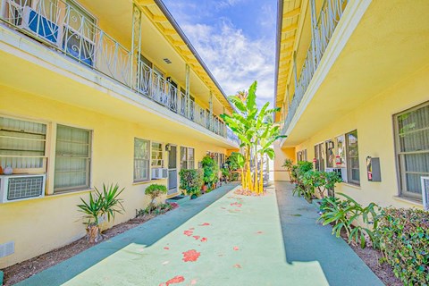 a courtyard between two yellow buildings with a blue walkway