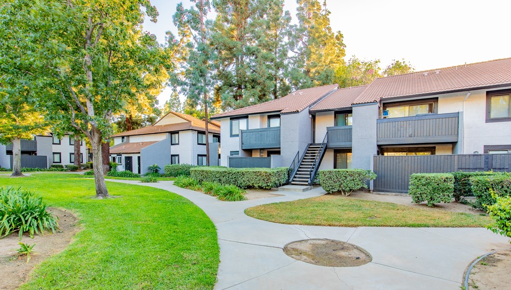 a group of apartment buildings with a yard and sidewalk