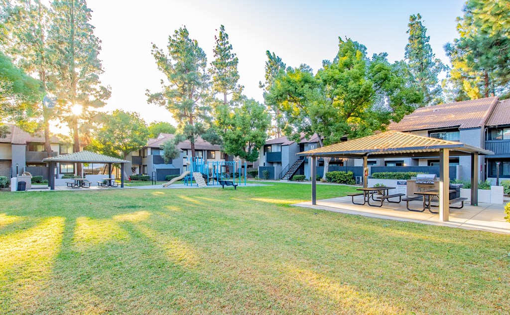 a park with picnic tables and buildings with trees