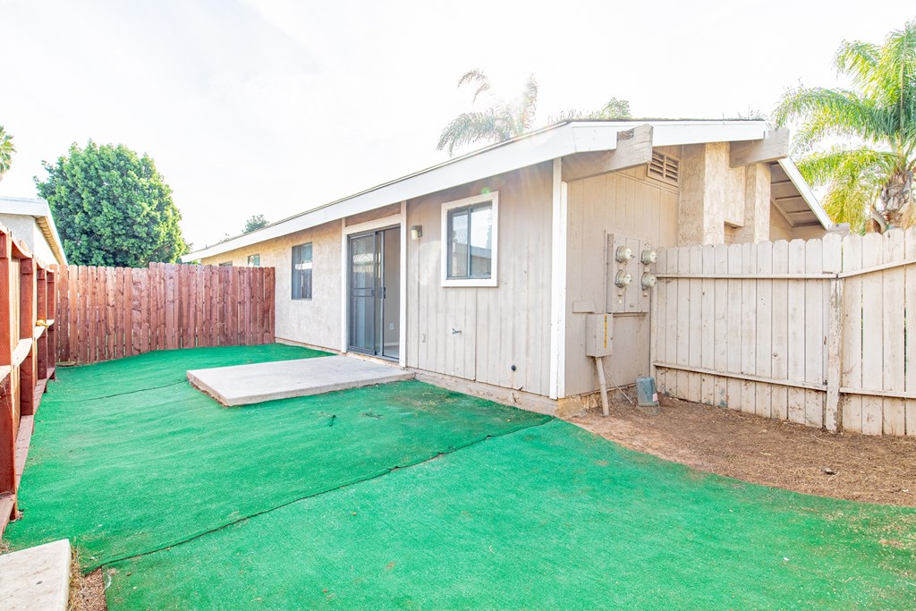 the backyard has a green lawn and a small house