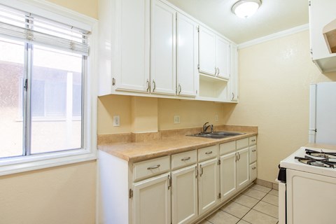 A kitchen with white cabinets and a beige countertop.