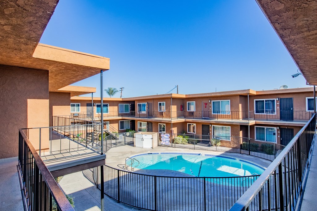 A pool in a courtyard surrounded by a black fence.