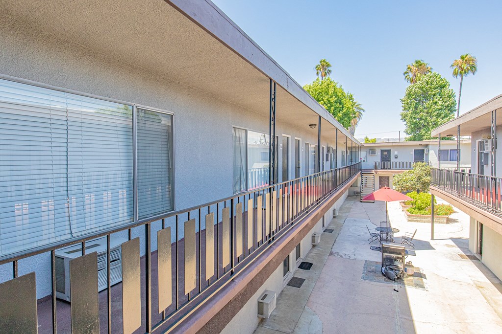 a long balcony with tables and chairs at a building with windows