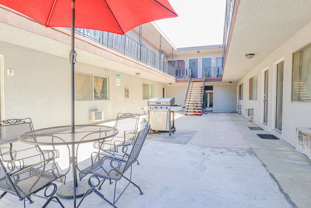 a patio with a table and chairs and a red umbrella