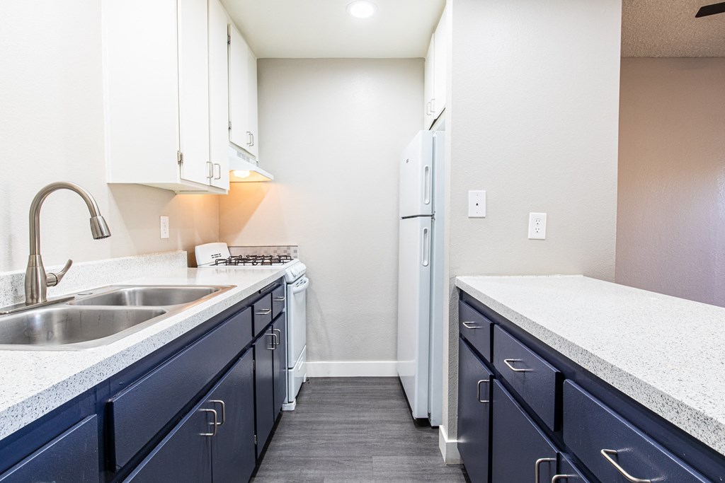 an empty kitchen with blue cabinets and a sink and a refrigerator