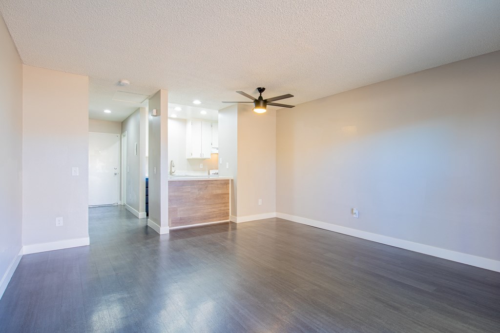 an empty living room with wood floors and a ceiling fan