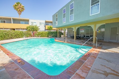 a swimming pool in front of a building with a resort style pool