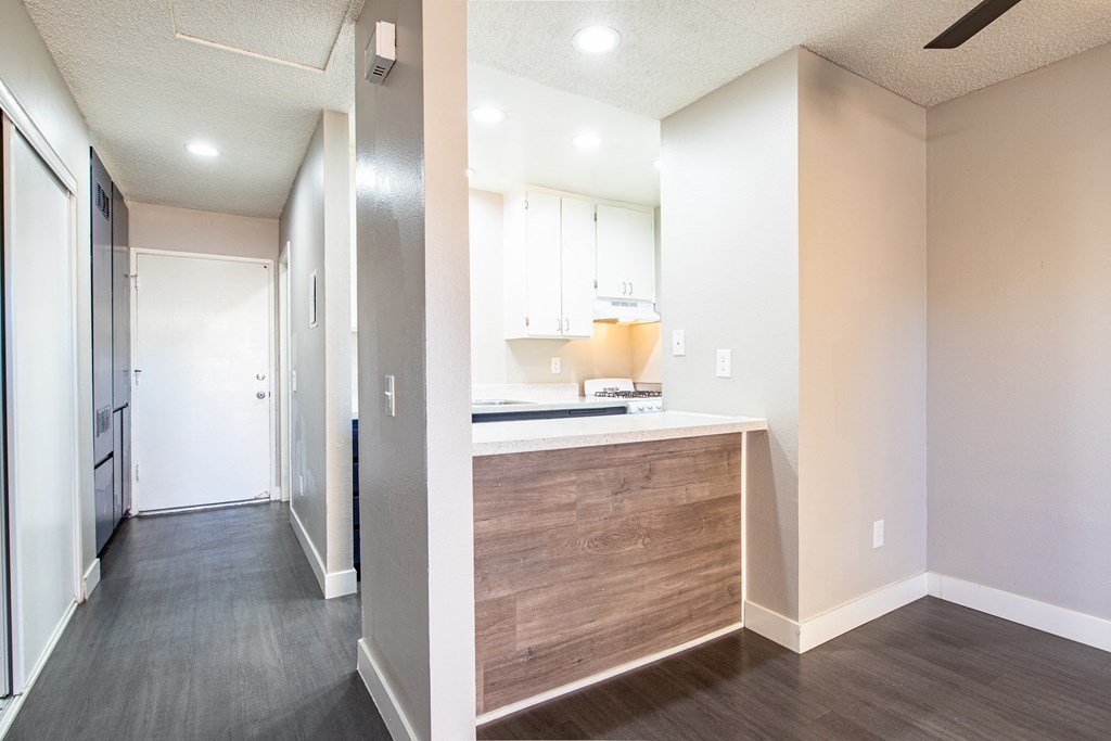 a renovated kitchen with white cabinets and wood flooring and a hallway with a door