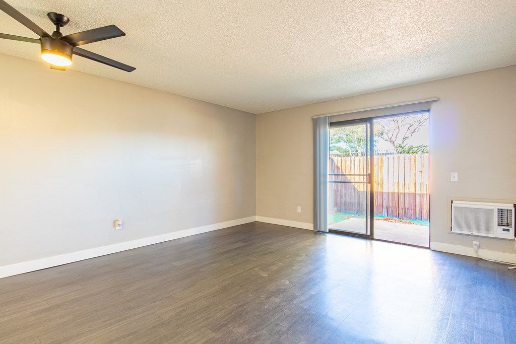 an empty living room with a sliding glass door to a patio