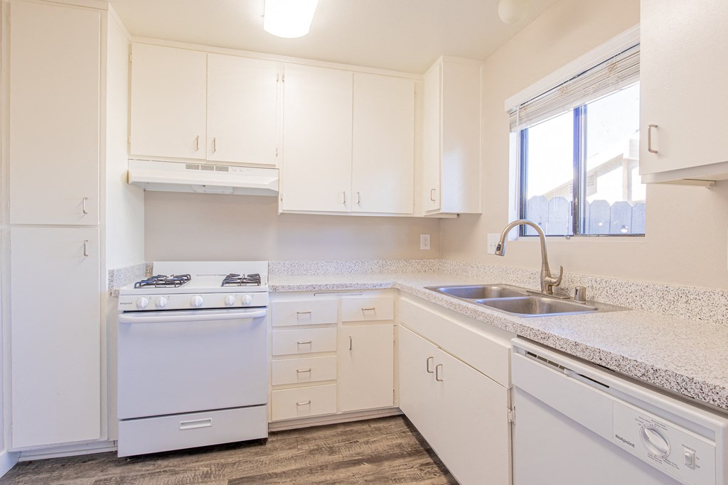 a kitchen with white cabinets and a sink and a window