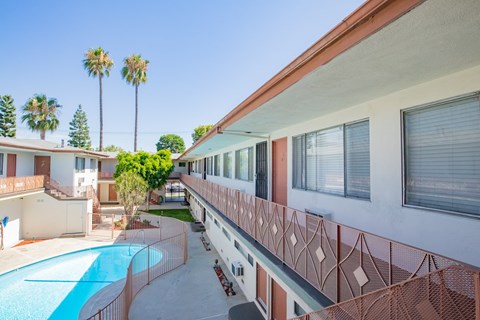 a balcony with a pool and a building with palm trees