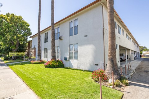 a white building with a green lawn and palm trees