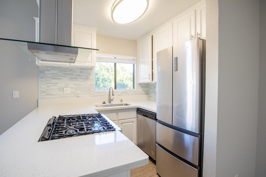 an updated kitchen with stainless steel appliances and white countertops