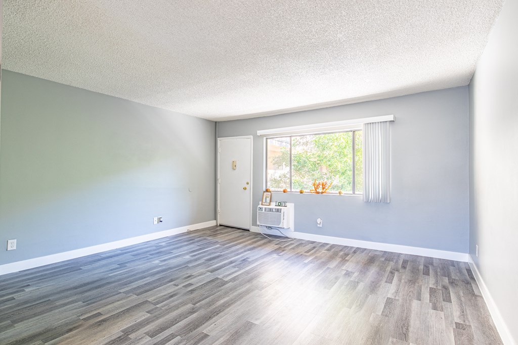 an empty living room with wood floors and a window