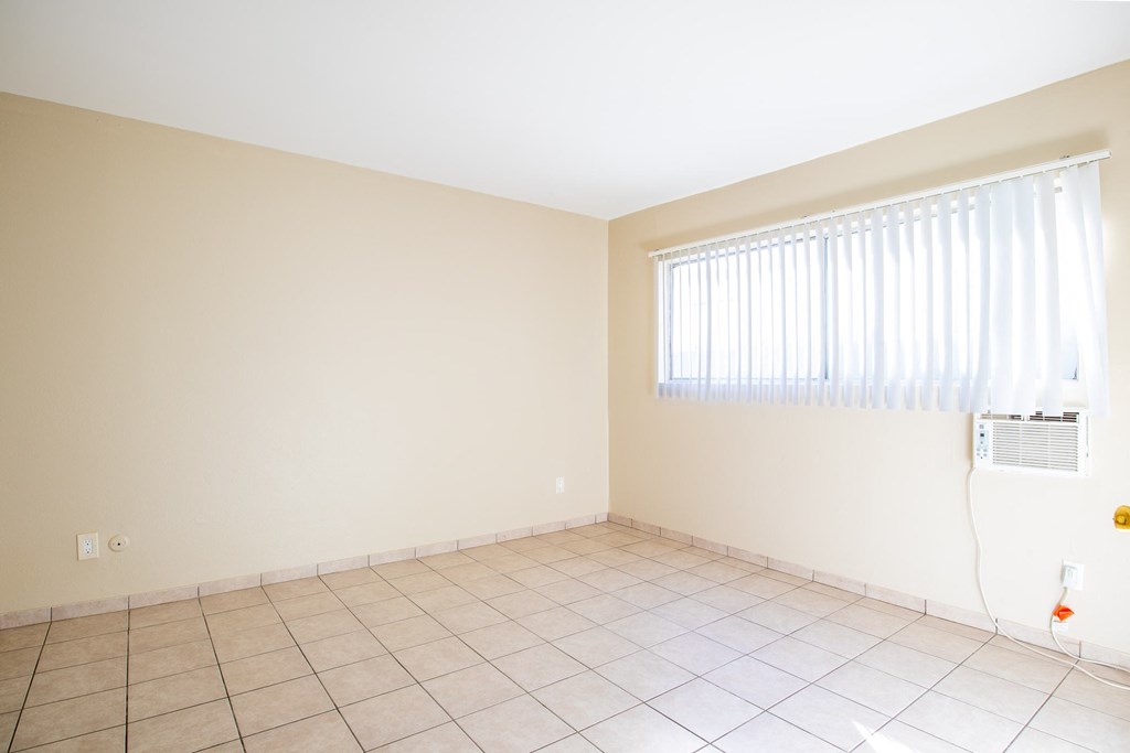 an empty room with a window and a tiled floor