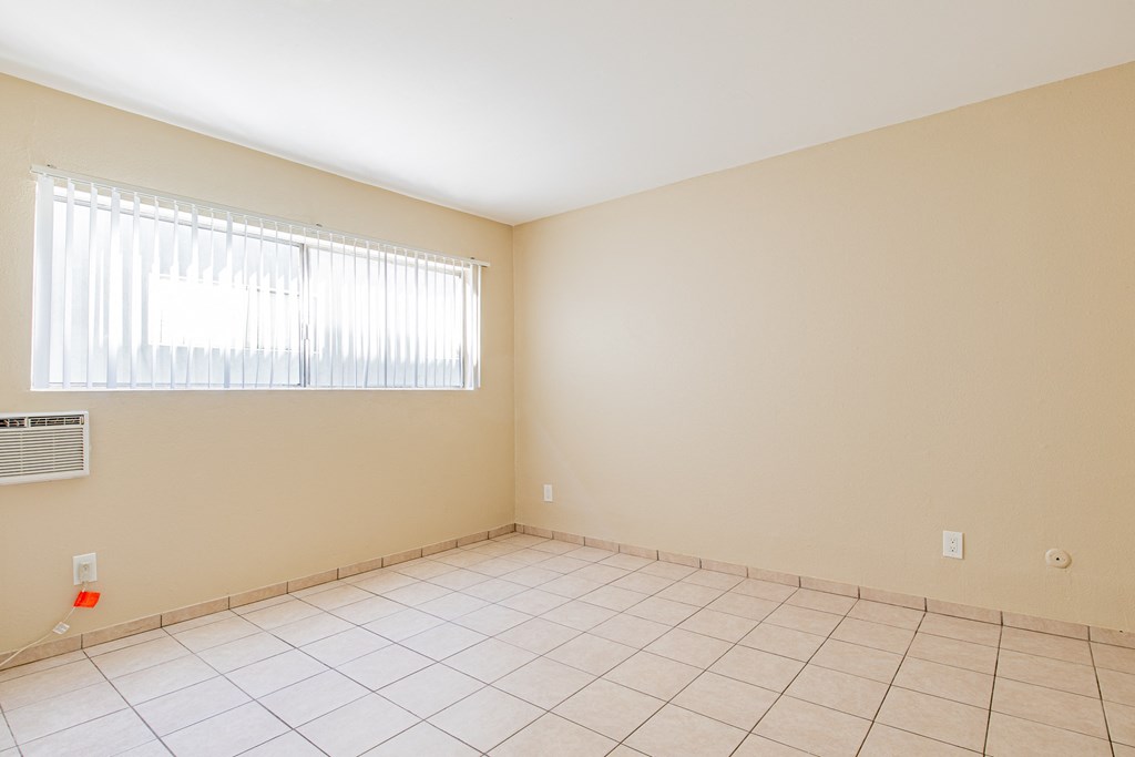 an empty room with a window and a tiled floor