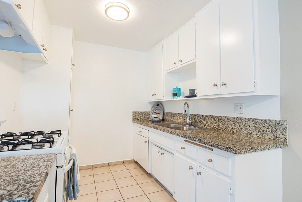 a kitchen with white cabinets and granite counter top and a stove