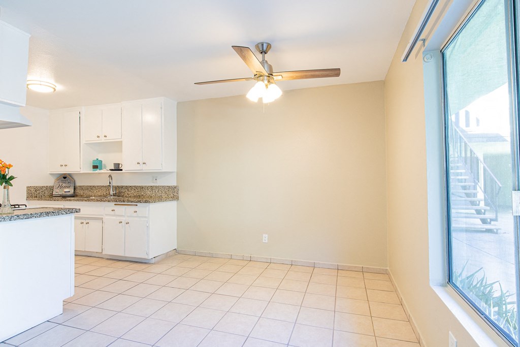 an empty kitchen with a ceiling fan and a window