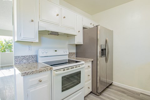 A kitchen with white cabinets and a stainless steel refrigerator.