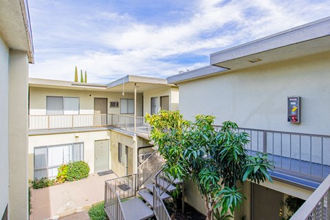 an apartment building with stairs and a balcony and plants