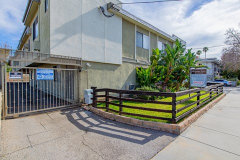 an apartment building with a fence and a sidewalk in front of it