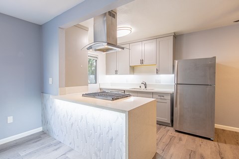 A modern kitchen with a stainless steel refrigerator and a white island.