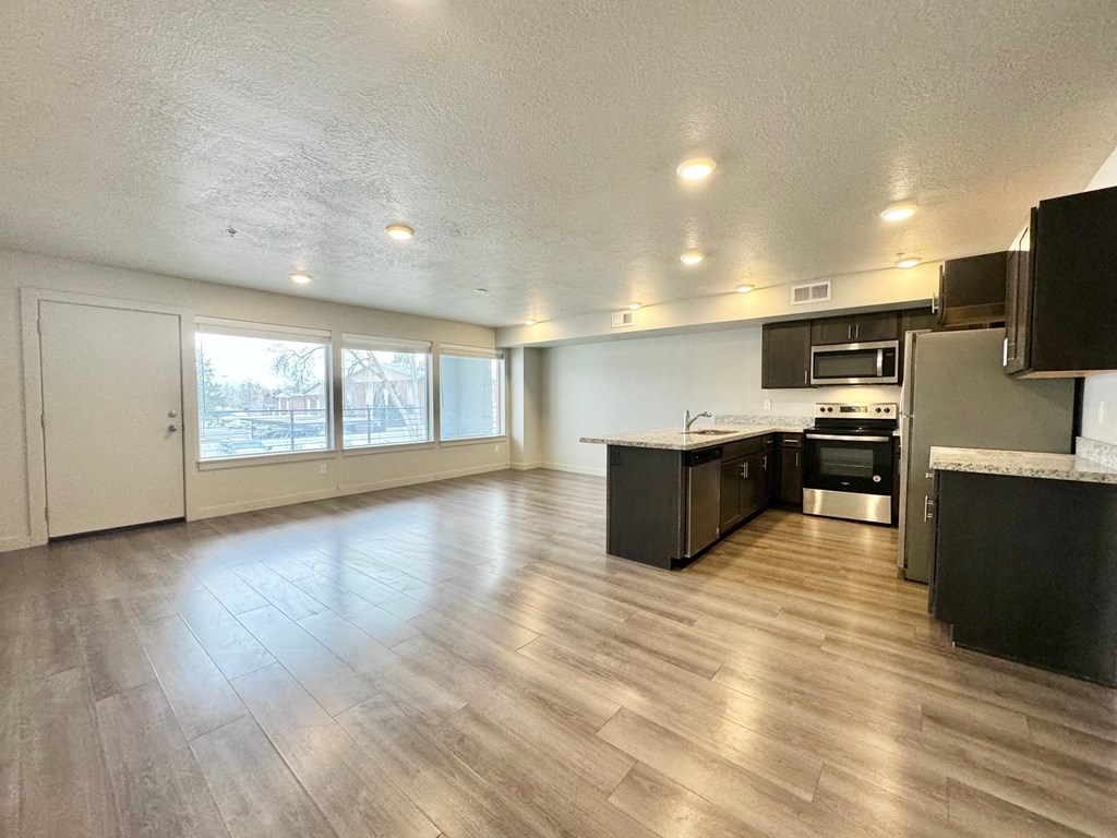 an empty kitchen and living room with a wood floor