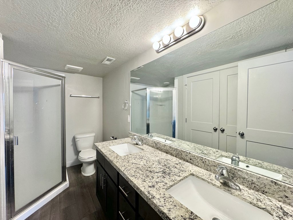 a bathroom with two sinks and a shower and a toilet