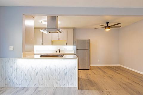 A kitchen with a stainless steel refrigerator and a stainless steel range hood.