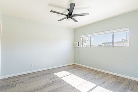 an empty room with a ceiling fan and a window