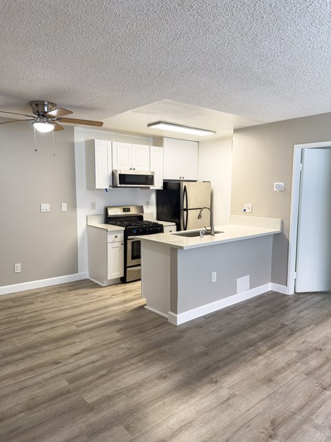 A kitchen with a white counter and a black stove top.