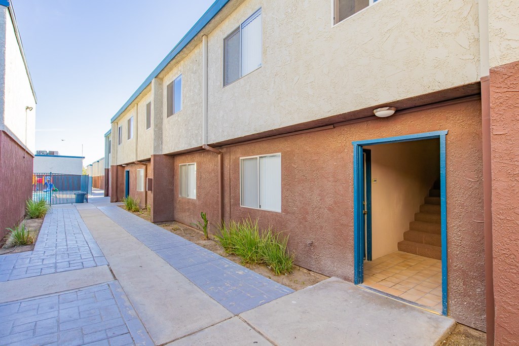 an empty sidewalk in front of a building with blue doors