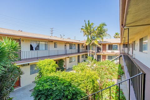 A sunny day at a residential building with balconies and green plants.