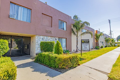 a pink building with a sign on it and a sidewalk