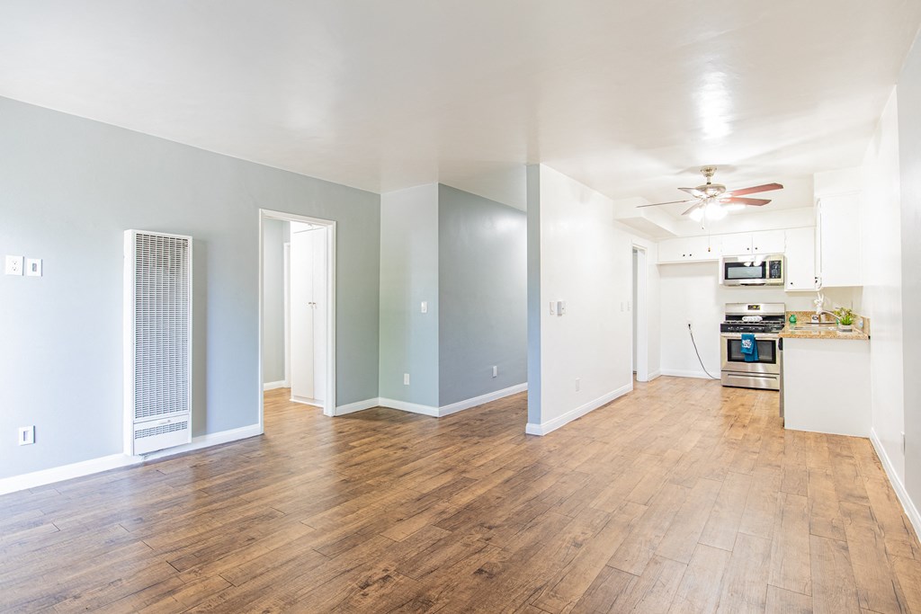 A room with a ceiling fan and a kitchenette in the corner.