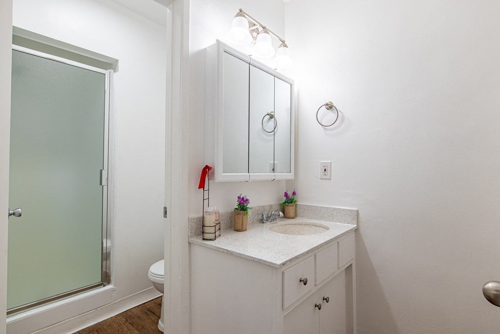 A white bathroom with a sink and mirror.