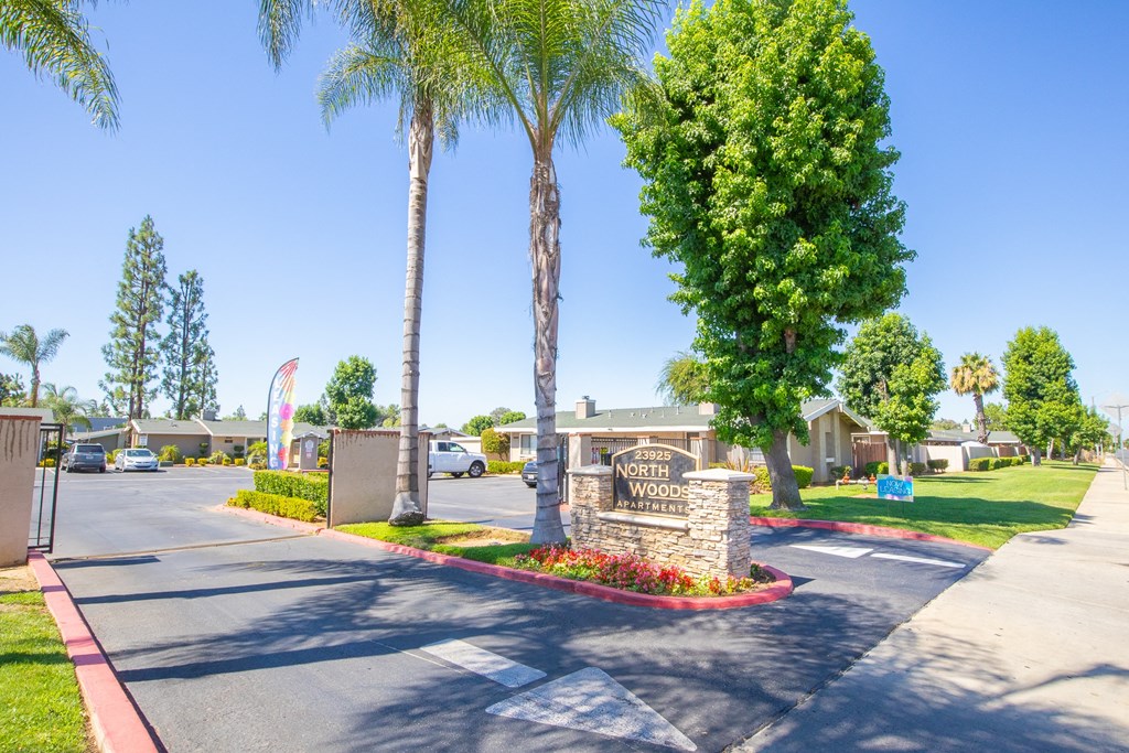 a street with a sign and palm trees in front of a building