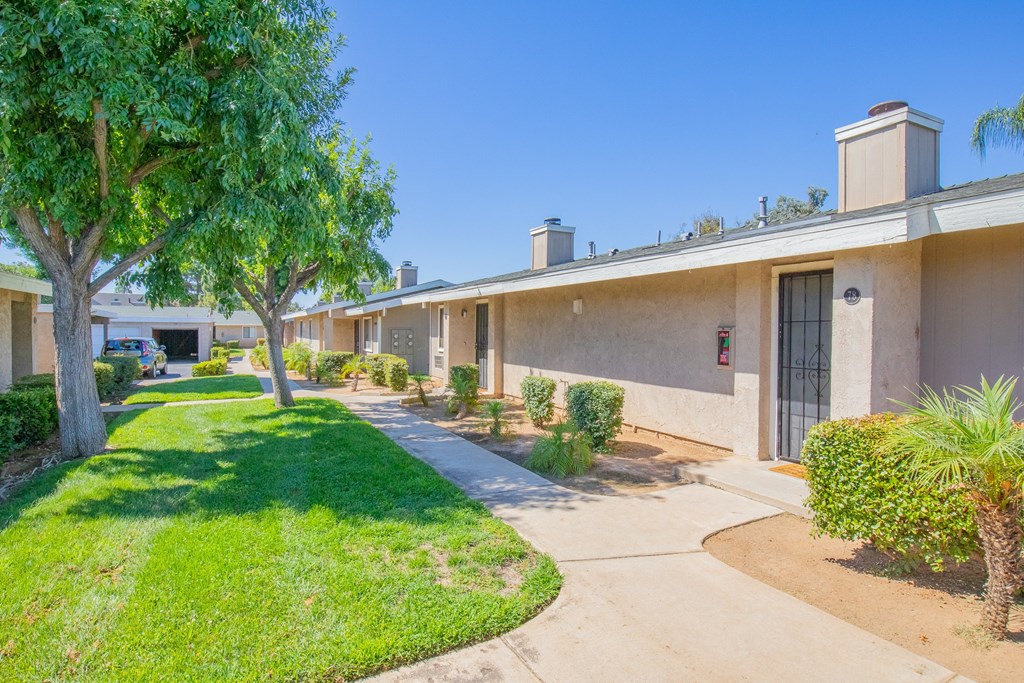 a building with a sidewalk and trees in front of it