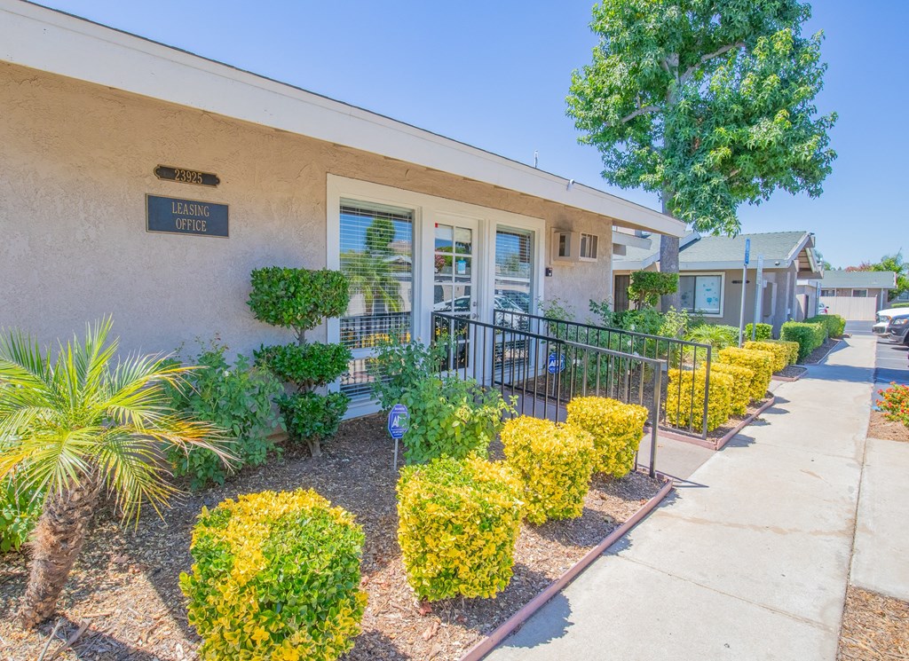 a building with a sidewalk and landscaping with plants and trees