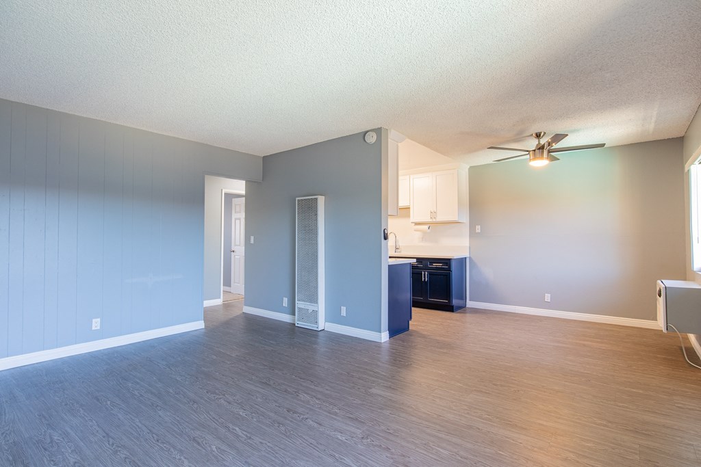 A spacious room with a ceiling fan and a kitchenette.