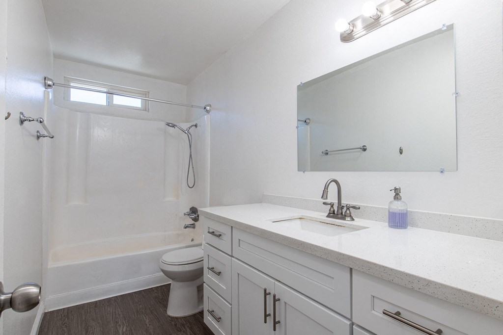A white bathroom with a toilet, sink, and shower.