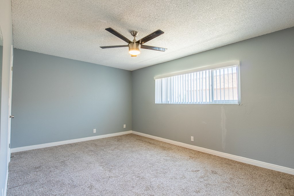 A room with a ceiling fan and a window with blinds.