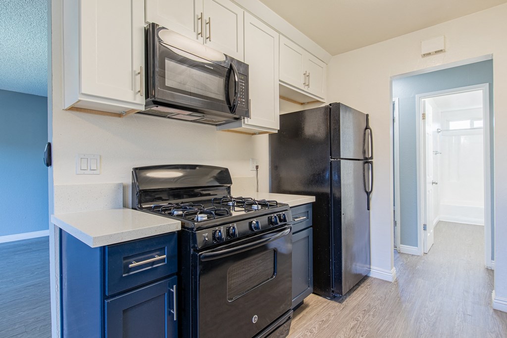 A kitchen with black appliances and white cabinets.