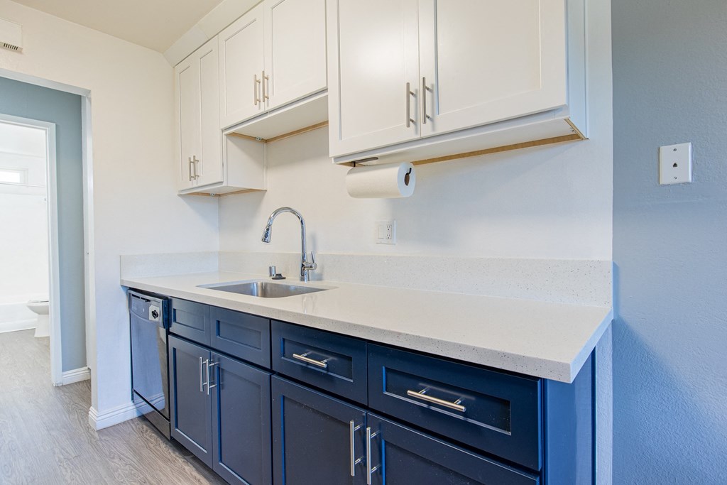 A kitchen with blue cabinets and a white counter.