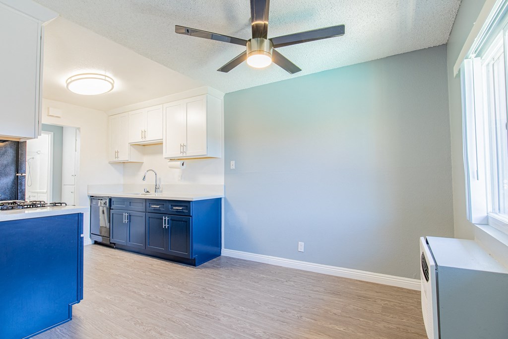 A kitchen with blue cabinets and a ceiling fan.